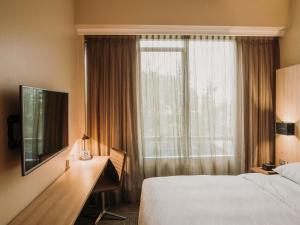 a hotel room with a bed and a desk and a window at Mercure Concepcion in Concepción
