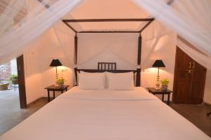 a bedroom with a large white bed with two lamps at Dhyana Beach Villa in Ambalangoda