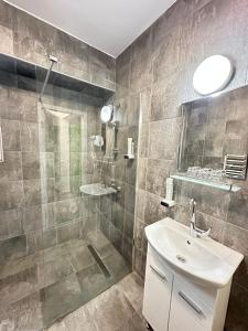 a bathroom with a shower and a sink and a mirror at Бутик хотел ресторант брасери и релакс зона Сажитариус in Kyustendil