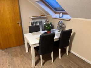 een witte eettafel met stoelen en een dakraam bij Eifelnest Stadtkyll in Stadtkyll