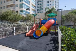 a playground with a slide in a park at Apto Frente Mar Bali Beach Home Club 3 Quartos Climatizados Cozinha Completa Sacada com Churrasqueira 2 Vagas de Garagem Piscina borda infinita Sauna Academia Cinema Quadra Salão de Jogos Pé na Areia 15min do Beto Carrero in Piçarras