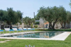 una piscina con tumbonas y árboles en un patio en Trulli Piccoli by Raro Villas, en Locorotondo