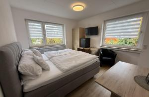 a bedroom with a bed and a table and two windows at Gästehaus Fries in Blankenheim