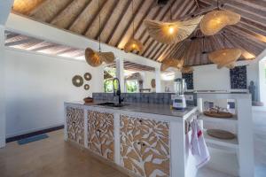 a kitchen with a island in a room with wooden ceilings at OMAÏA Private villas in Amed