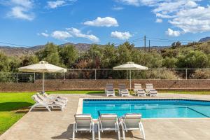 una piscina con tumbonas y sombrillas junto a una piscina en Lucy Lux Villa, en Milatos