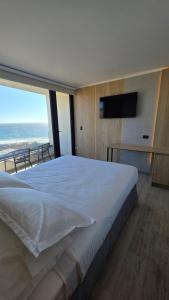 a bedroom with a large white bed and a television at Arka Hotel in Viña del Mar