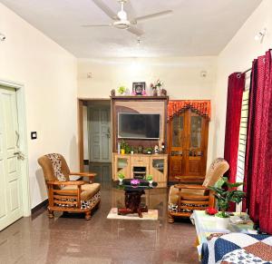a living room with a television and chairs at Swasthiks Home stay in Sakleshpur