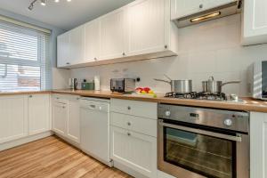 a kitchen with white cabinets and a stove top oven at Hideaway in Swanage