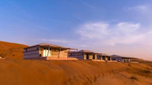 a row of houses on top of a sand hill at Desert Escape Camp Wahiba in Ibrā