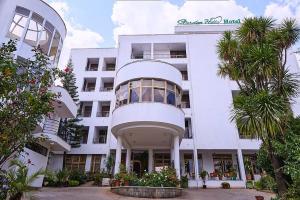 a white building with palm trees in front of it at Garden Hills Hotel in Addis Ababa