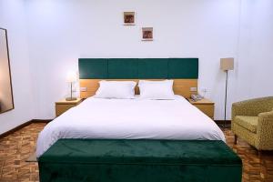a bedroom with a large bed with a green headboard at Garden Hills Hotel in Addis Ababa +2 photos