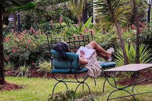 a woman sitting in a chair reading a book at Garden Hills Hotel in Addis Ababa