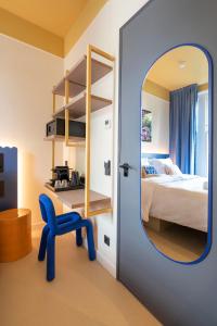 a bedroom with a mirror and a blue chair at City Hotel Rembrandt Square - Just renovated in Amsterdam