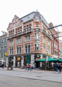 a large brick building with people walking in front of it at City Hotel Rembrandt Square - Just renovated in Amsterdam +47 photos