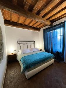 a bedroom with a bed with blue sheets and a window at Villa Tiberini - Wine Relais in Torrita di Siena +16 photos