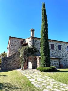 a large stone building with a tree in front of it at Villa Tiberini - Wine Relais in Torrita di Siena
