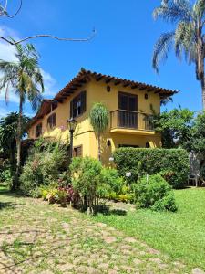een geel huis met een balkon en palmbomen bij Hospedaria Da Nadia in Paraty