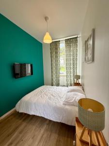 a bedroom with a white bed and a green wall at Résidence Bonnecaze in Eaux-Bonnes
