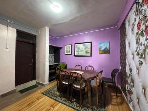 comedor con paredes de color púrpura, mesa y sillas en Nembang Family homestay, en Darjeeling
