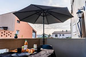 una mesa con comida y una sombrilla en el balcón en Love Room La Magie d'une Nuit, en Agde
