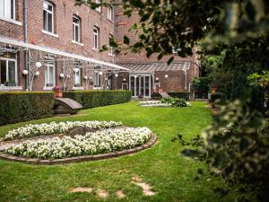 un jardín con flores blancas frente a un edificio en Mercure Liege City Centre, en Lieja
