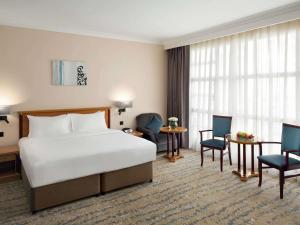 a hotel room with a bed and a desk and chairs at Anwar Al Madinah Mövenpick in Al Madinah +232 photos