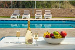 un bol de fruta y una botella de vino y copas en Lucy Lux Villa, en Milatos