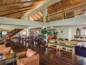 a large living room with wooden ceilings and tables and chairs at Mövenpick Hotel & Residences Nairobi in Nairobi
