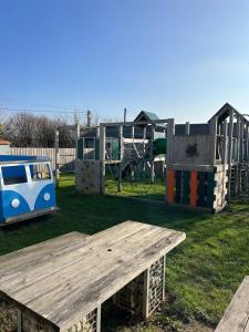 Un parque con una mesa de picnic de madera y un parque infantil. en Beautiful Holiday Home Close to the Sea, en Poughill