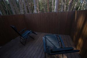 Una terraza con dos sillas y una bolsa y árboles. en 1日1組限定 森の高級プライベートサウナ付きヴィラテント 早朝サウナプラン, en Fujikawaguchiko