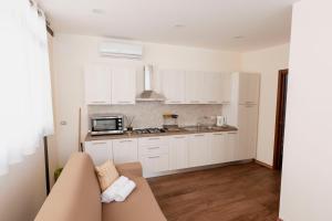 a kitchen with white cabinets and a couch in a room at Luna di Sale - Romantic Sea Rooms & Apartments in Reggio di Calabria
