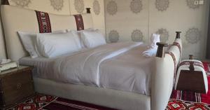 a bed with white sheets and pillows in a bedroom at Desert Escape Camp Wahiba in Ibrā