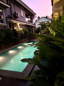 a swimming pool with lights in front of a house at Beijo do Sol, Goa Private Pool Luxury Villa in Jāmb
