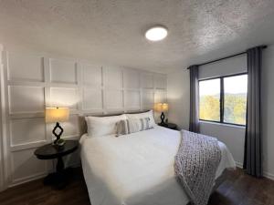 a bedroom with a white bed with two lamps and a window at Turkey Nest By Beyond Expectations Renovated 2br in Gatlinburg +40 photos