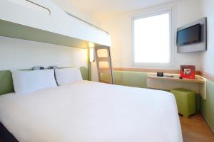 a hotel room with a bed and a window at ibis budget Metz Sud in Augny