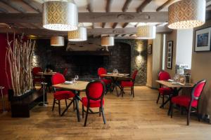 a restaurant with wooden tables and red chairs at Logis Hotel Spa Restaurant Au Site Normand in Clécy