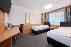 ein Hotelzimmer mit zwei Betten und einem Schreibtisch in der Unterkunft Hotel Ganslhof - Adults only in Salzburg