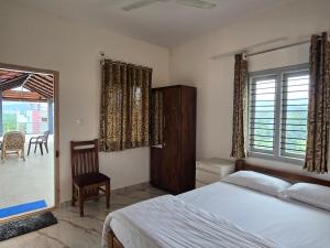 une chambre avec un lit, une chaise et une fenêtre dans l'établissement Evergreen Shola View, à Chikmagalur