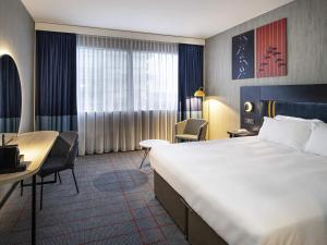 a hotel room with a large bed and a desk at Mercure Antwerp City South in Antwerp