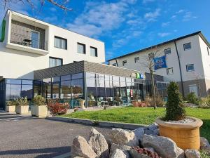 a building with glass windows and rocks in front of it at ibis Styles Le Treport Mers Les Bains in Mers-les-Bains