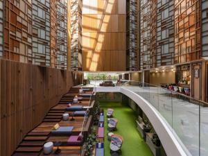 a building with a long corridor with tables and chairs at ibis Styles Bangkok Silom in Bangkok