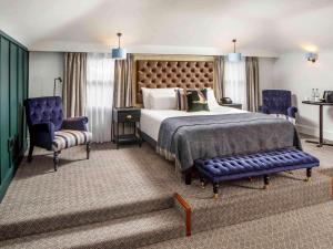 a bedroom with a large bed and two blue chairs at Mercure Oxford Hawkwell House Hotel in Oxford