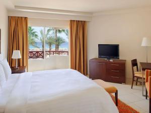 a hotel room with a large bed and a television at Naama Bay Promenade Beach Resort Managed By Accor in Sharm El Sheikh