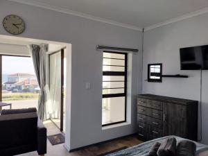 a bedroom with a clock on the wall and a window at Driftwoods in Gqeberha