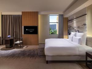 a hotel room with a large bed and a desk at Pullman Yueyang in Yueyang