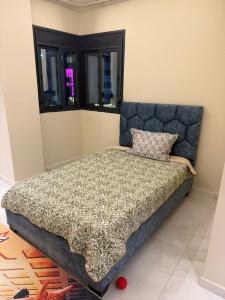 a bedroom with a bed with a blue headboard and windows at Résidence montana in Deli Ibrahim