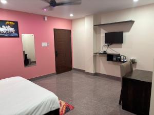 a bedroom with a pink wall with a bed and a flat screen tv at Stanza Premium Hotels in Bhubaneshwar