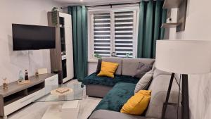a living room with a gray couch and yellow pillows at Apartament z jacuzzi w centrum Katowic in Katowice