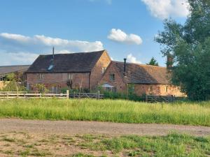 an old brick house with a fence in a field at The Stables in Droitwich