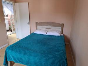 a bedroom with a bed with a blue blanket on it at Casa Ribeiro in Canguçu